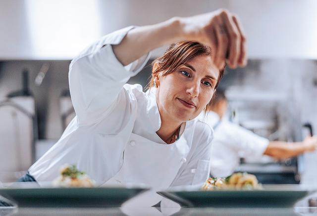 A chef garnishes a plate